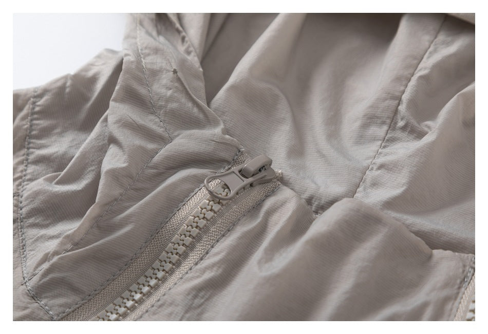 Close-up of the light taupe jacket's zipper pull, teeth, and stitched hood seam.