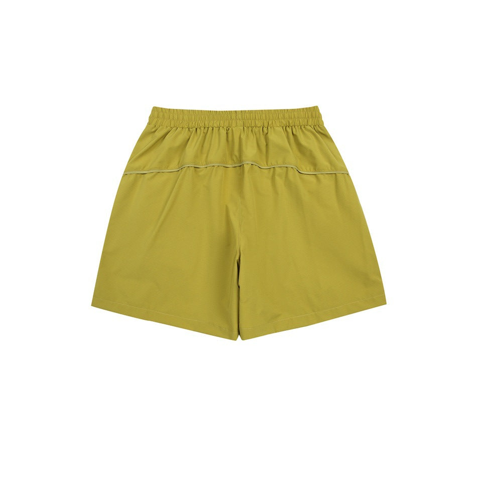 Mustard yellow-green athletic shorts, back view, with an elastic waistband and horizontal yoke seam.