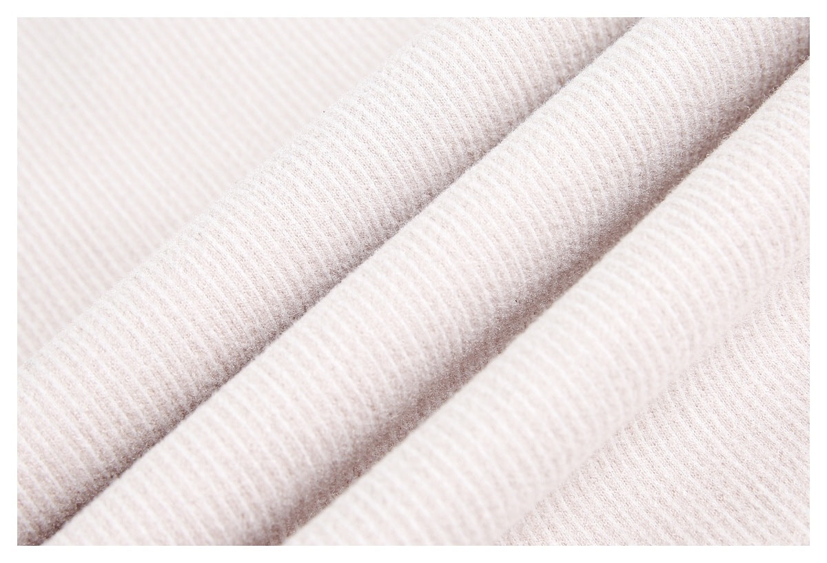 Close-up of pale ivory ribbed fabric draped in soft folds.