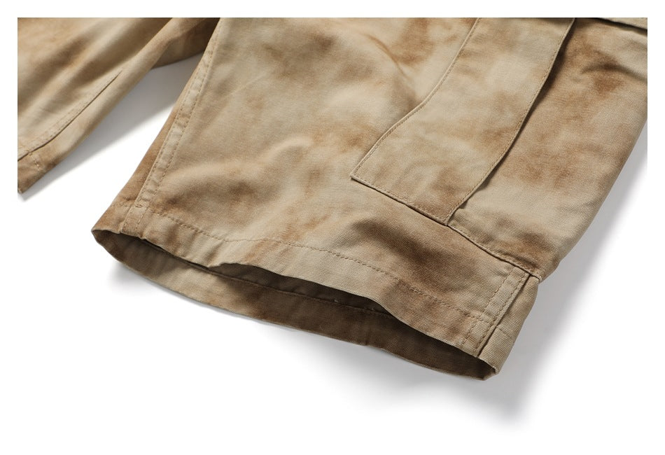 Close-up of a cargo pant leg hem and rectangular pocket in tan mottled fabric.