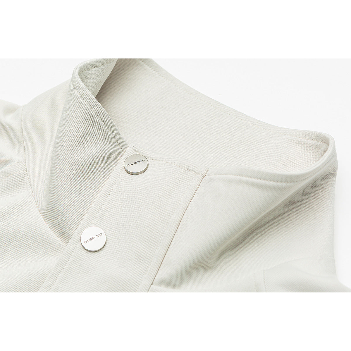 Close-up of an off-white jacket's stand collar and front placket with two round metal buttons.