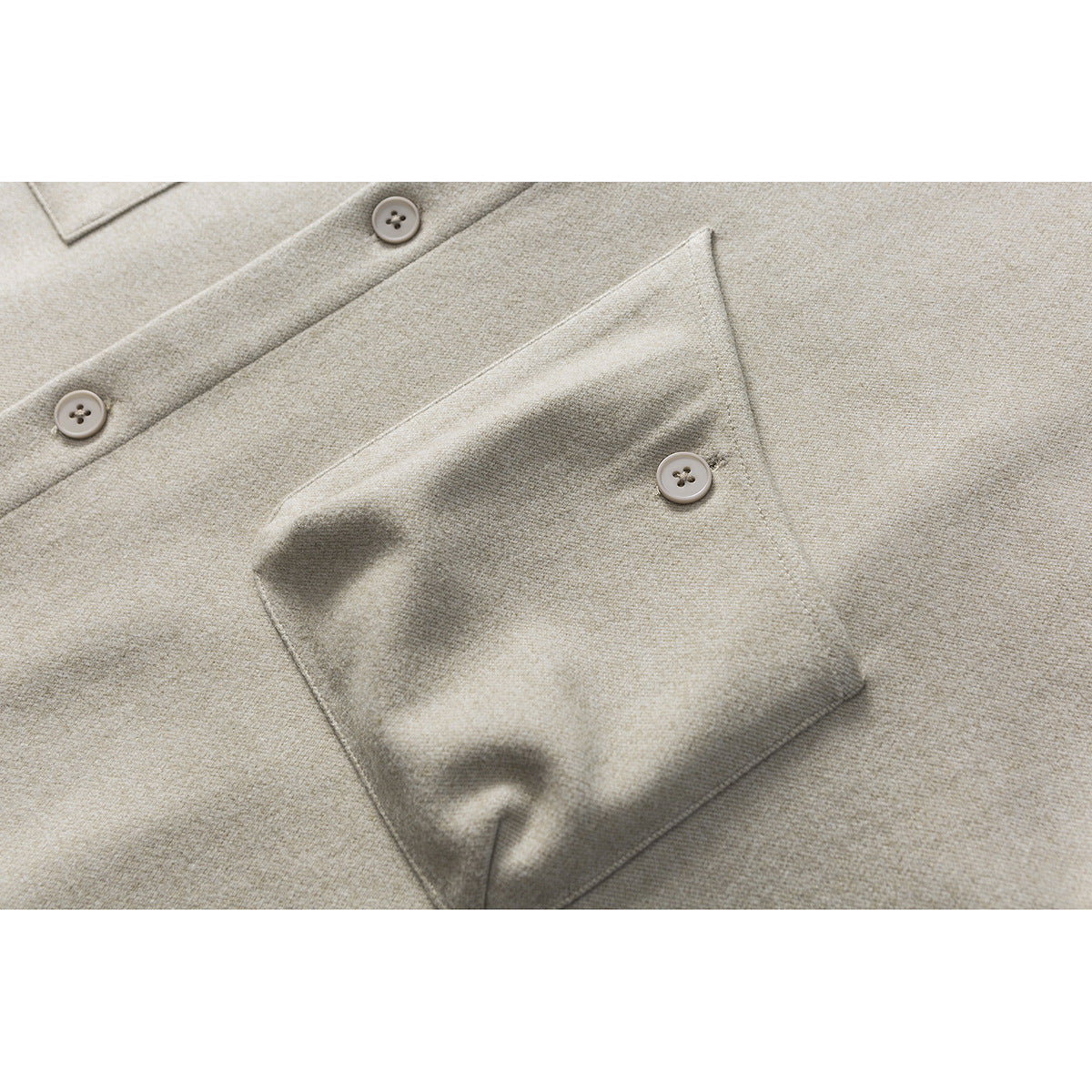 Close-up of a beige-gray shirt jacket’s button placket and large buttoned chest pocket.