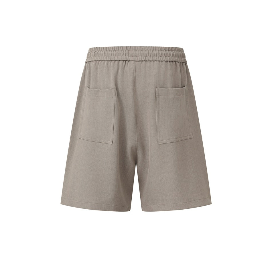 Rear view of taupe shorts with an elastic waistband and two patch pockets.