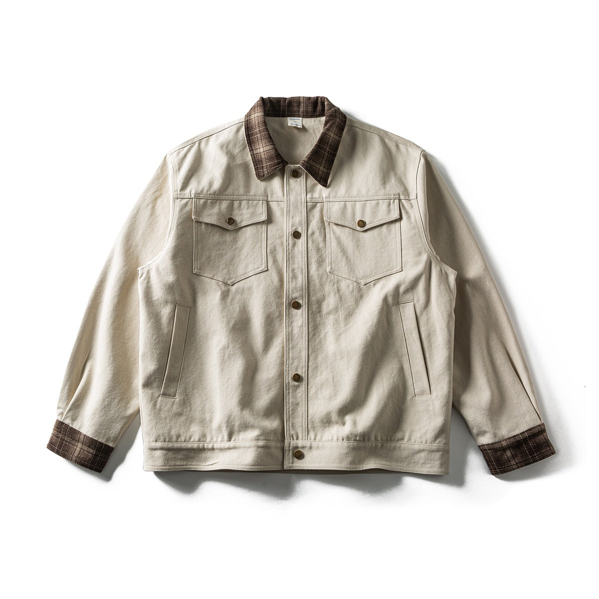 Off-white button-front jacket with brown plaid collar and cuffs, chest flap pockets and brass snaps, laid flat, front view