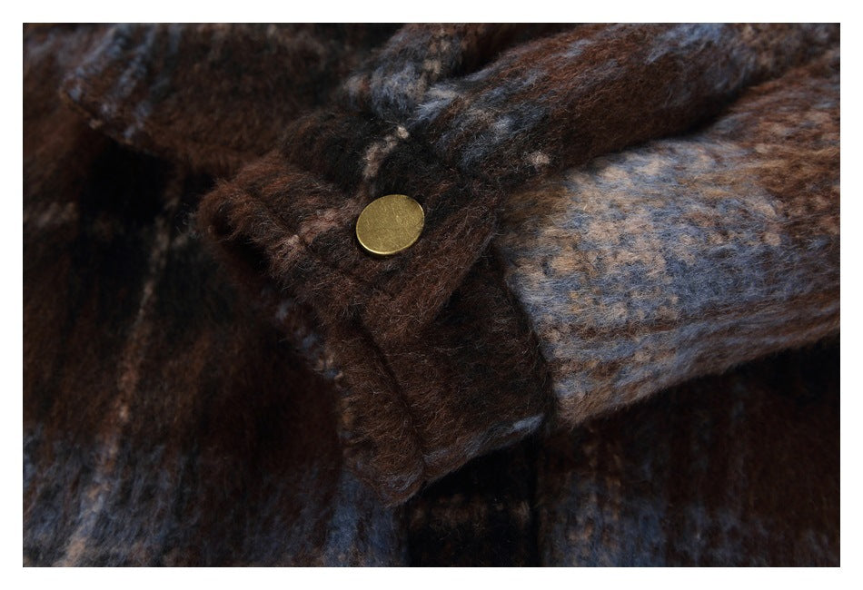 Close-up of a plaid coat cuff with a brass-colored snap button.