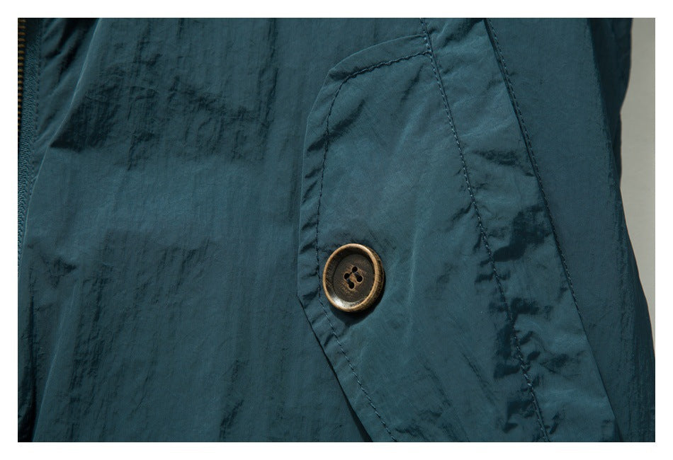 Close-up of a brown four-hole button on a dark teal garment, with visible stitching.