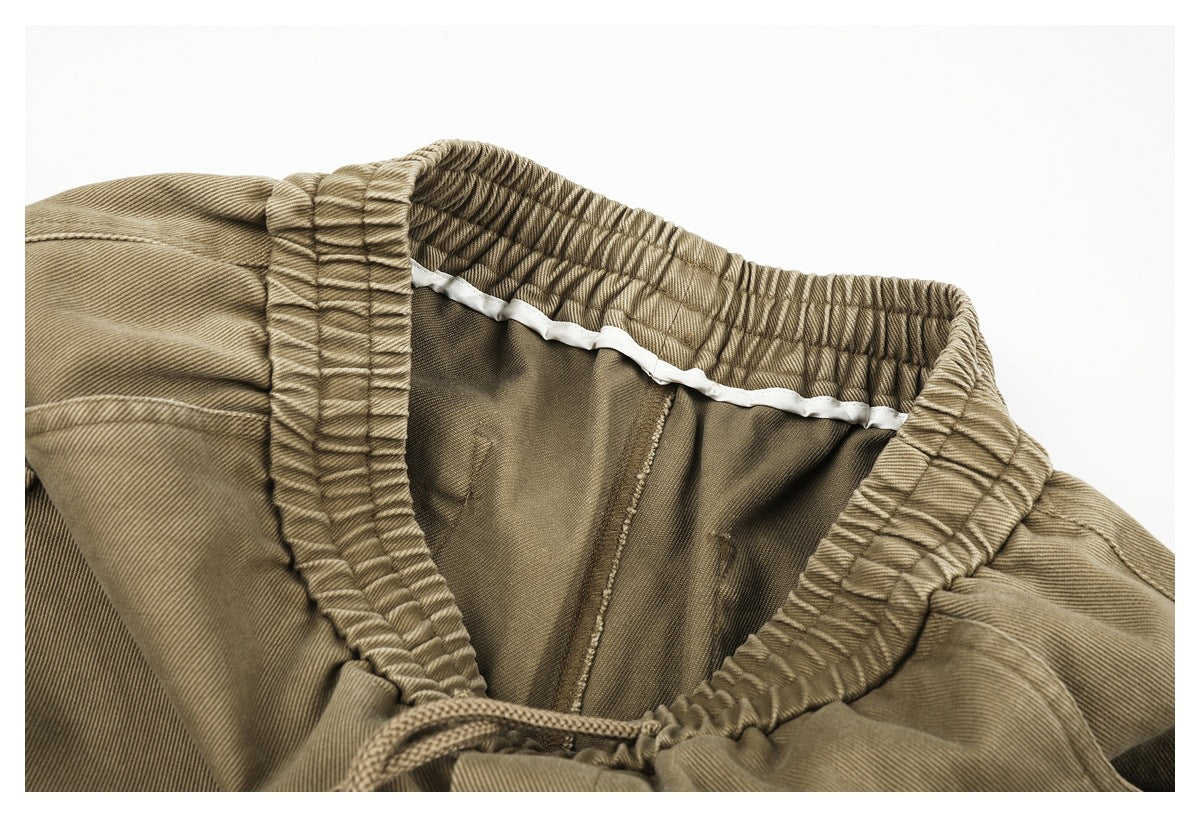 Close-up of the inside of tan trousers, showing the elastic waistband, lining, and drawstring.