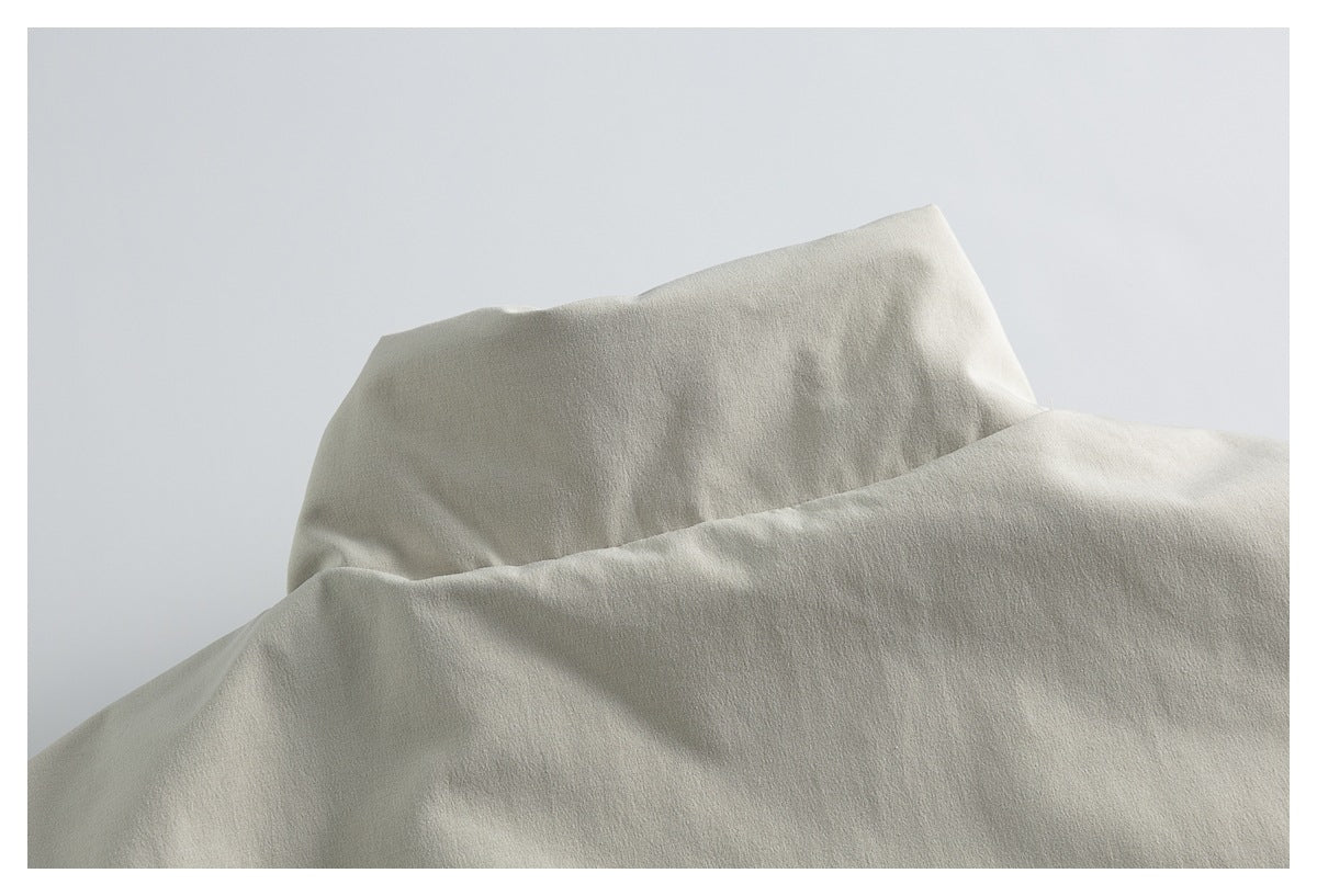 Close-up of the raised collar and upper back of a light beige jacket.