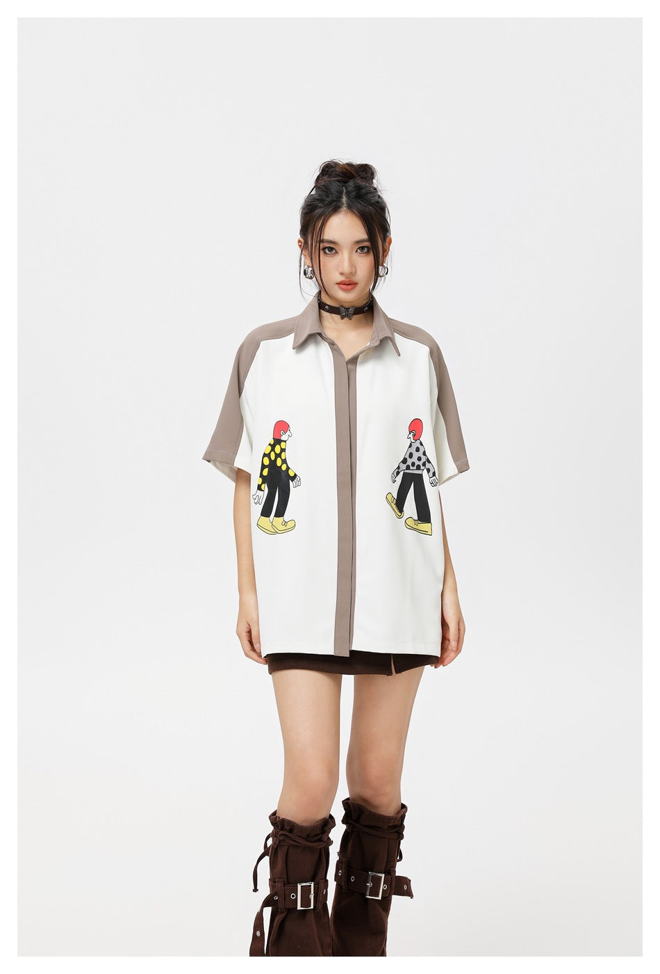 Front view of a model in a white oversized shirt with taupe trim and colorful cartoon prints on the front.