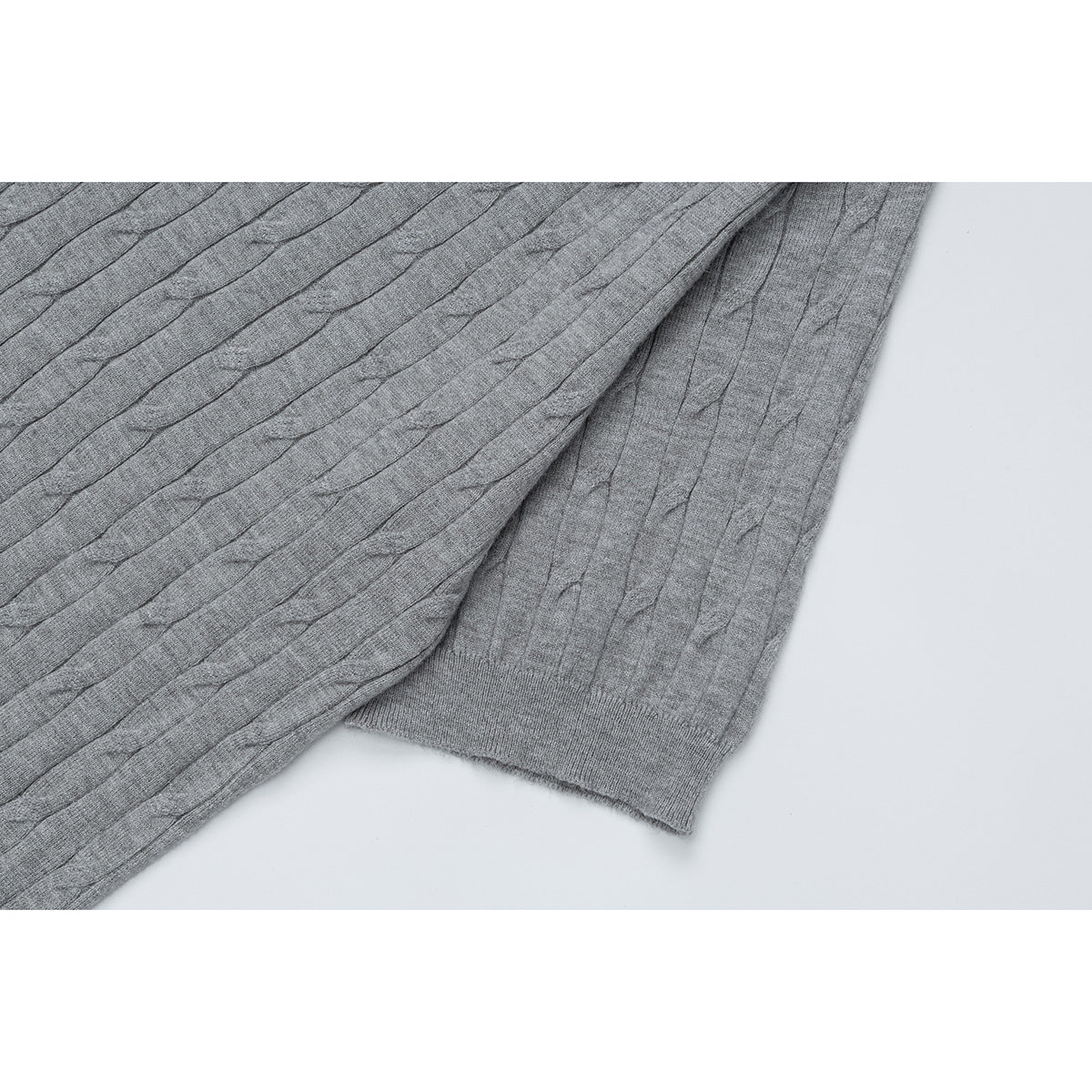 Close-up of a gray cable-knit top showing the sleeve cuff and ribbed hem.
