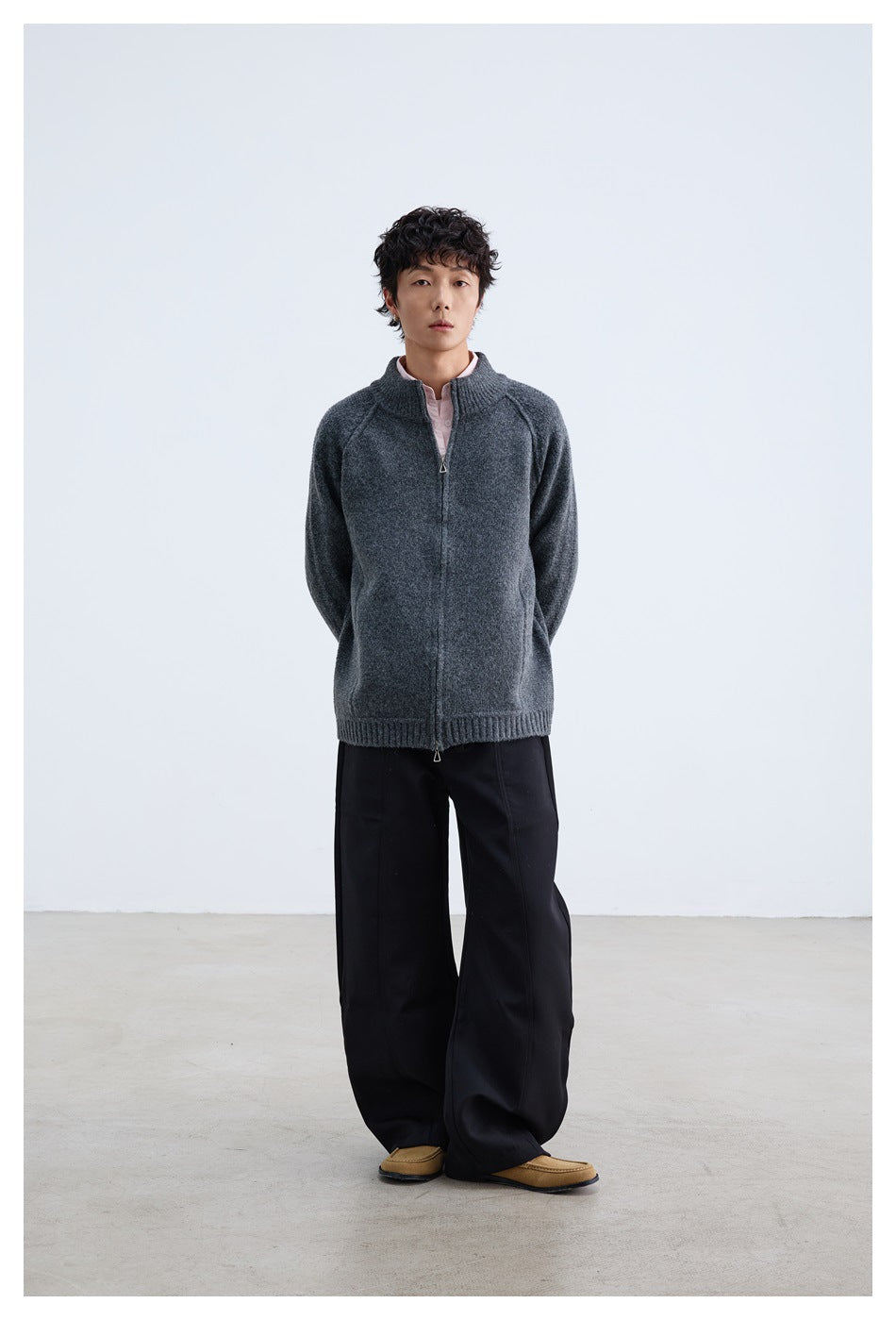 Full-length view of a model wearing a charcoal gray zip-front knit jacket and wide black trousers.