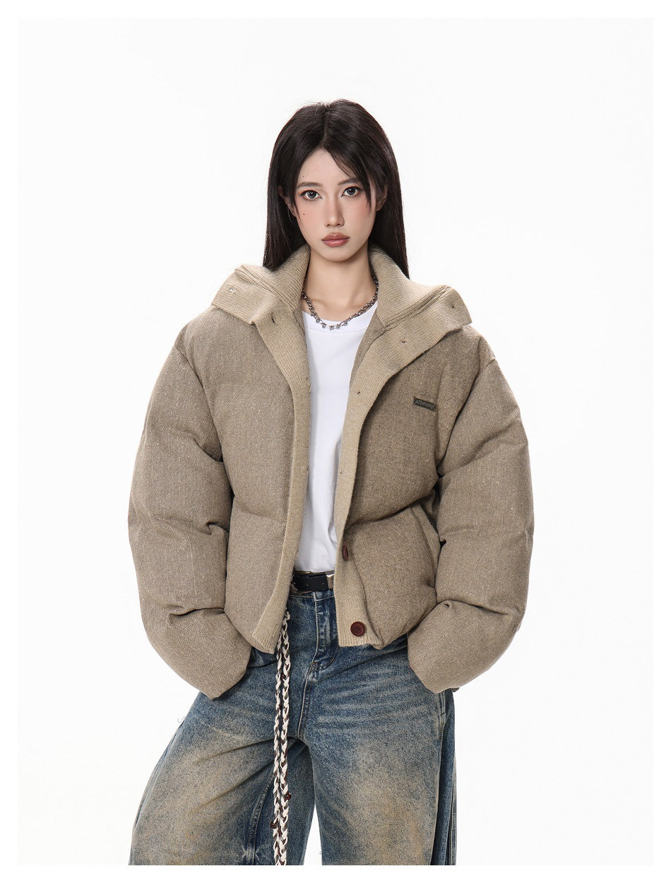 Close view of a model wearing a taupe padded jacket with an oversized contrasting collar and button front.