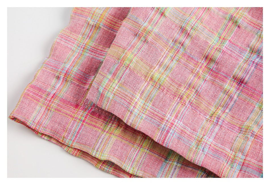 Close-up of a pink plaid garment showing a folded edge and layered seams.