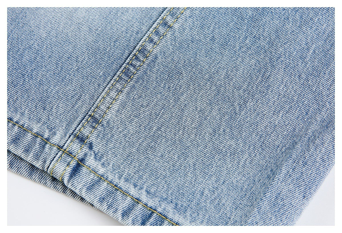 Close-up of light blue denim with a diagonal double-stitched seam and faded finish.