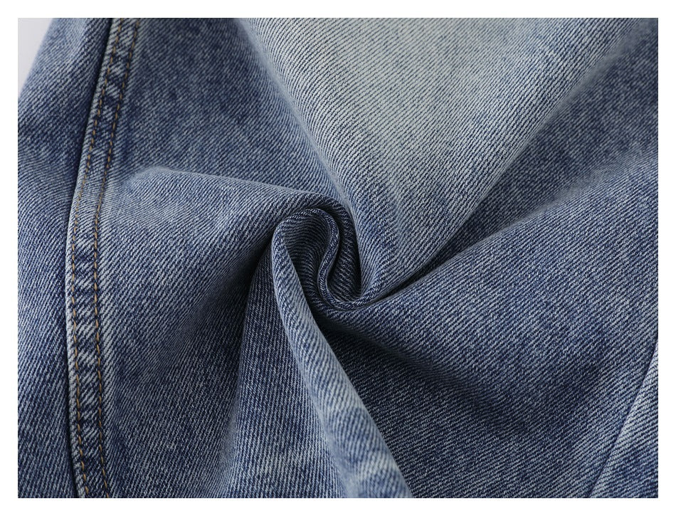 Close-up of blue denim gathered into a twist, showing its weave and double-stitched seam.