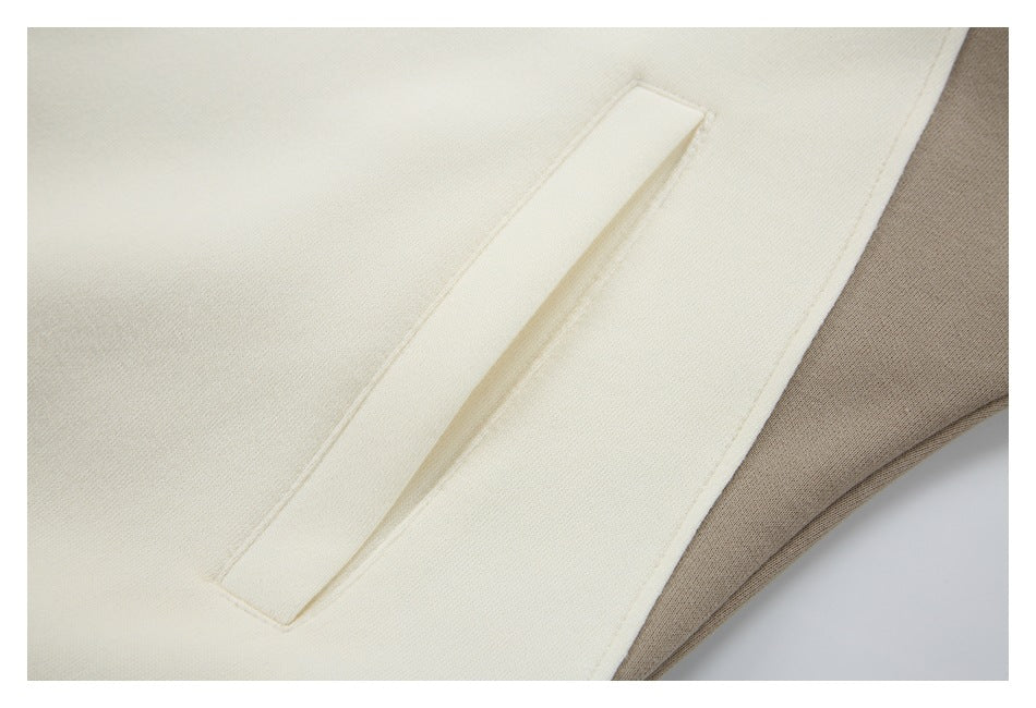 Close-up of a cream welt pocket beside a taupe panel on a color-block garment.
