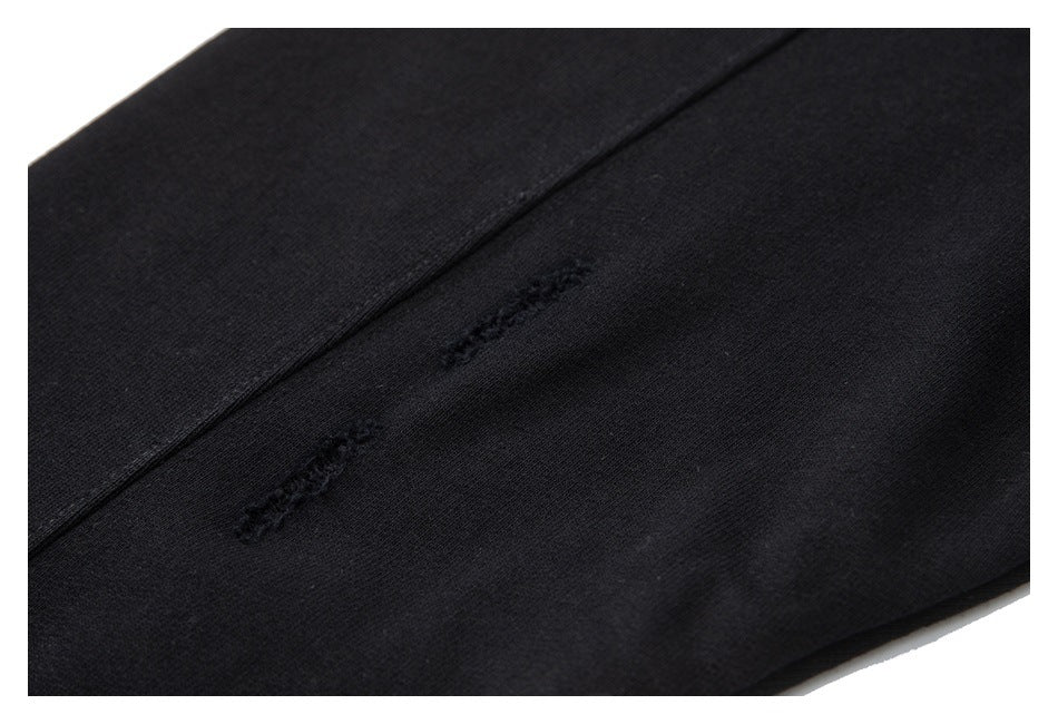 Close-up of black garment fabric with a seam and two small distressed stitched areas.