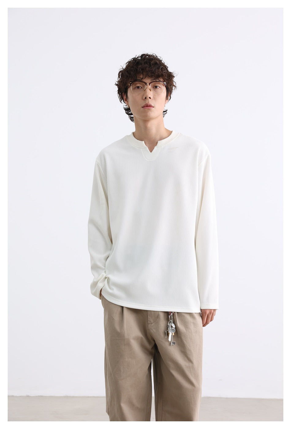 Front view of a model wearing an ivory ribbed long-sleeve top with a notched neckline and beige trousers.