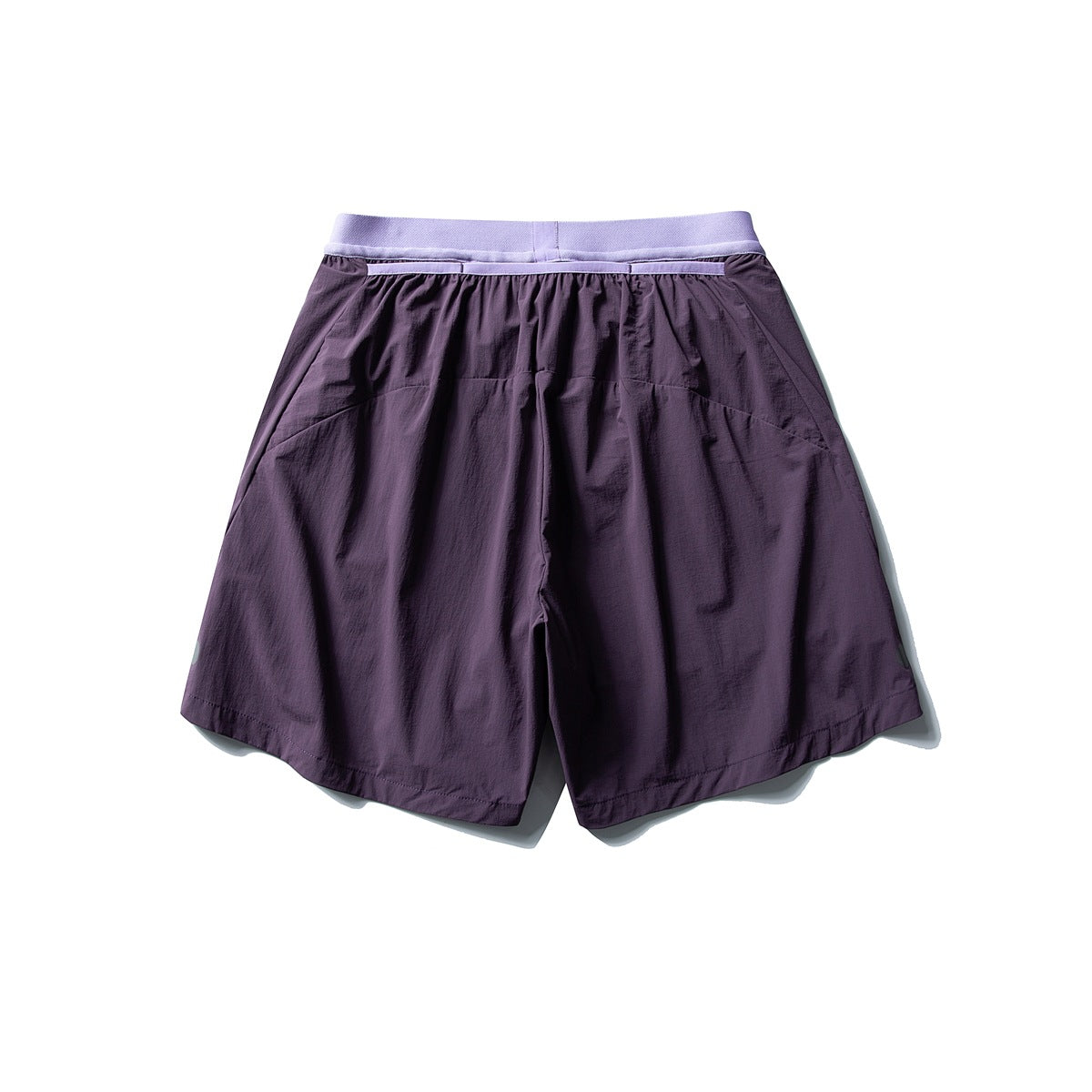 Back view of loose deep purple shorts with a pale lavender waistband and curved rear panel seams.