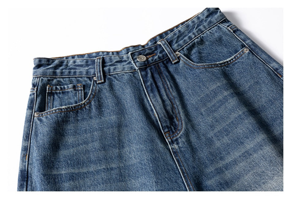 Cropped front view of blue washed jeans showing the waistband, button closure, pockets, and upper legs.