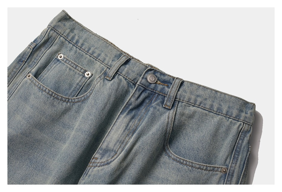 Close-up of the front waist and pockets of faded blue jeans, showing the button, belt loops, and coin pocket.