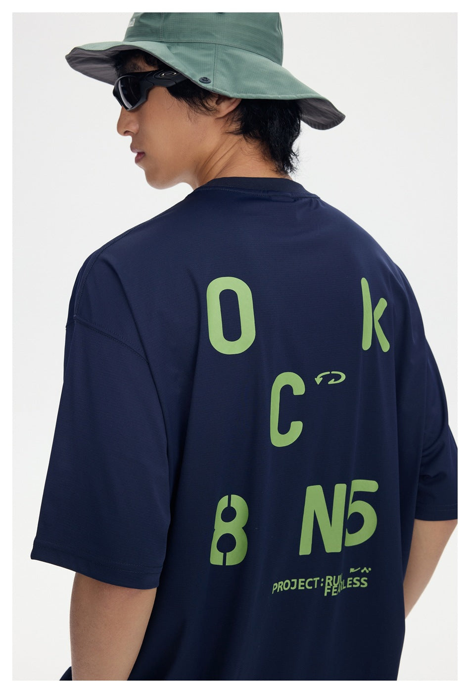Close-up of the navy T-shirt’s back, showing oversized lime lettering and graphic print.