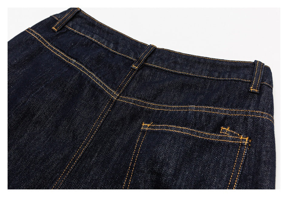 Close-up of dark indigo jeans showing the waistband, belt loops, yoke seam, and back pocket.