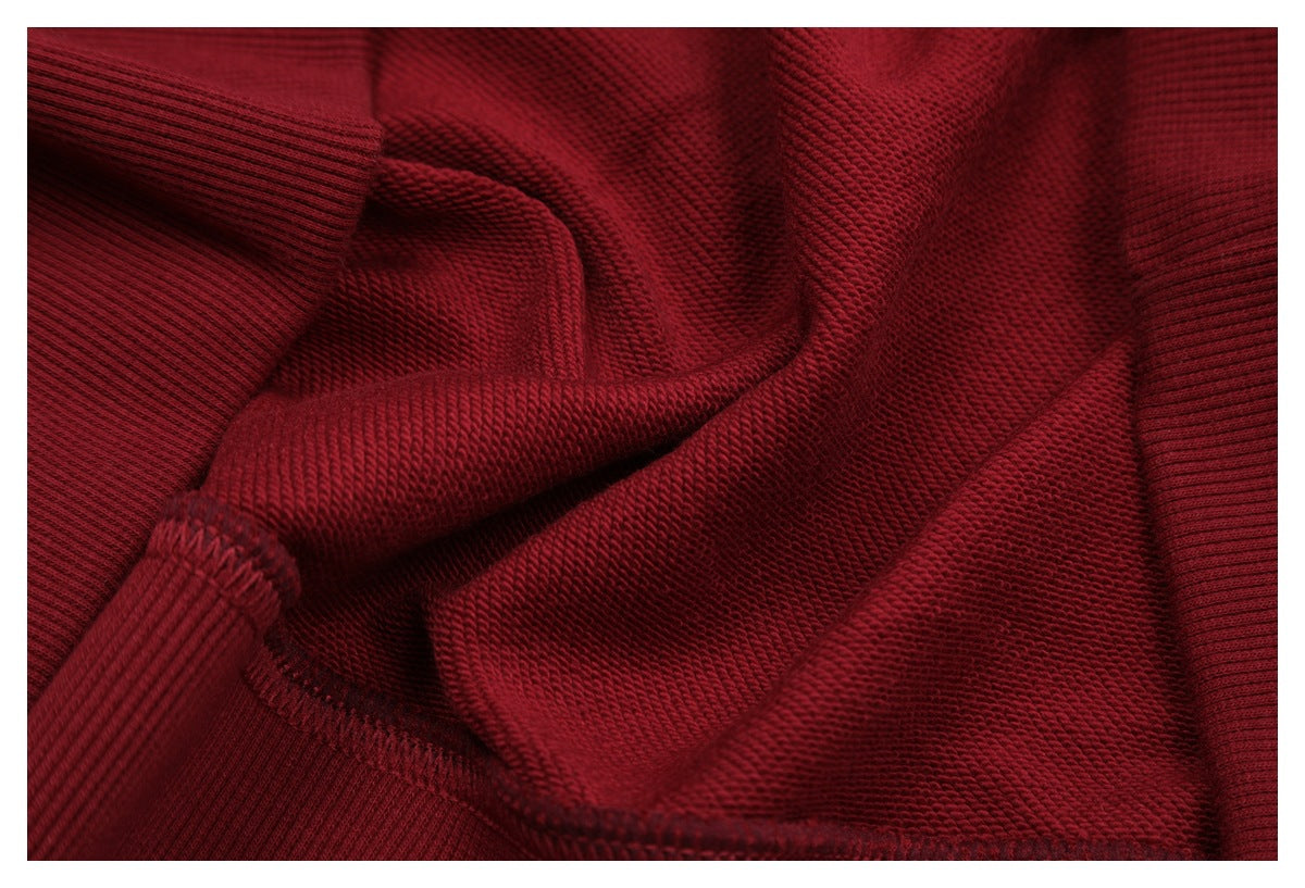 Close-up of deep red sweatshirt fabric, showing its knit texture and folded seam.