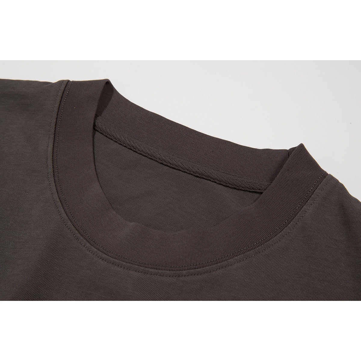 Close-up of a dark brown crew-neck shirt showing the ribbed collar and neckline stitching.