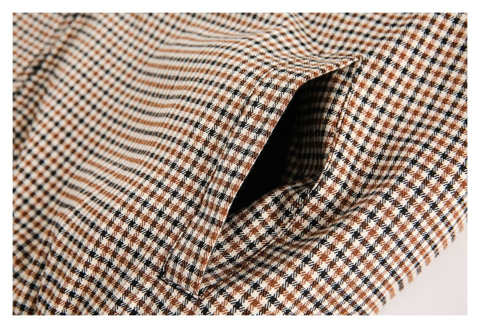 Close-up of a pocket opening in brown, black, and cream houndstooth fabric.