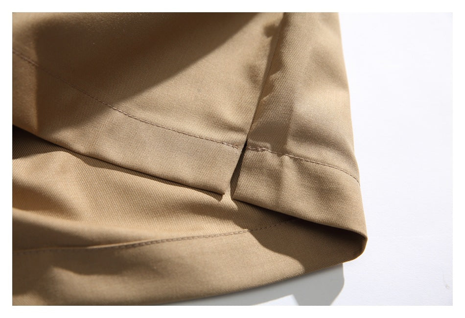 Close-up of a tan trouser leg showing the hem stitching and side slit.