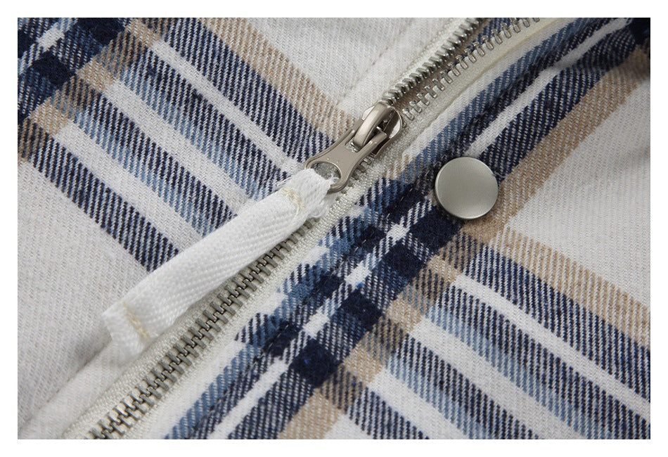 Close-up of the jacket's metal front zipper and snap button against cream, navy, and tan plaid.