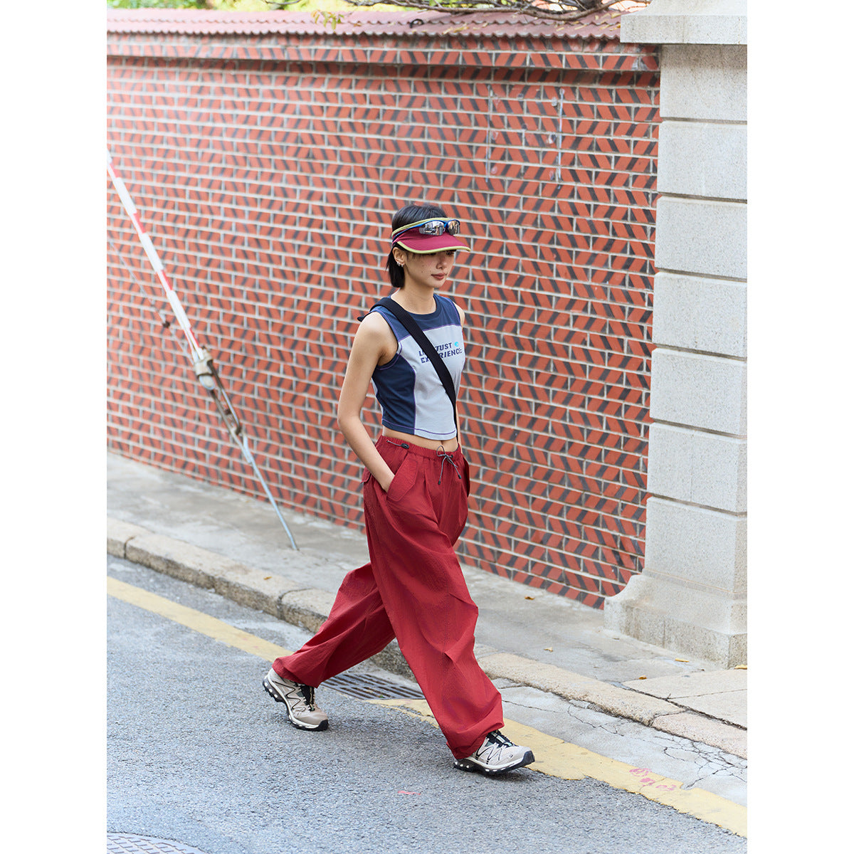 Model walking in loose red wide-leg pants and a navy-and-white sleeveless crop top.