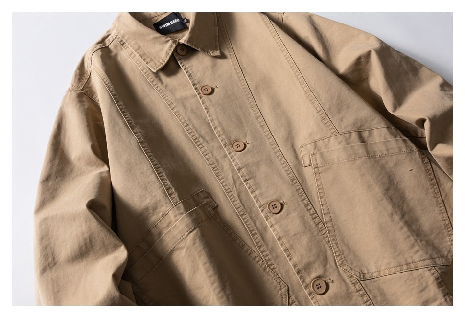 Tan button-front jacket laid flat, showing its collar, long sleeves, stitched panels, and large front pockets.
