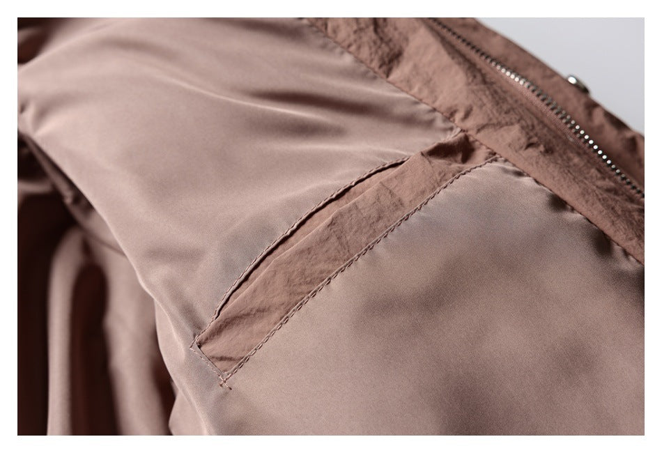Close-up of a brown garment pocket seam beside a metal zipper.