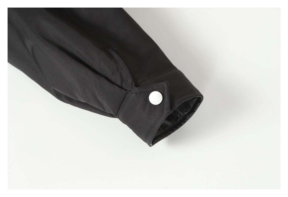 Close-up of a black jacket sleeve cuff with a silver snap fastener.