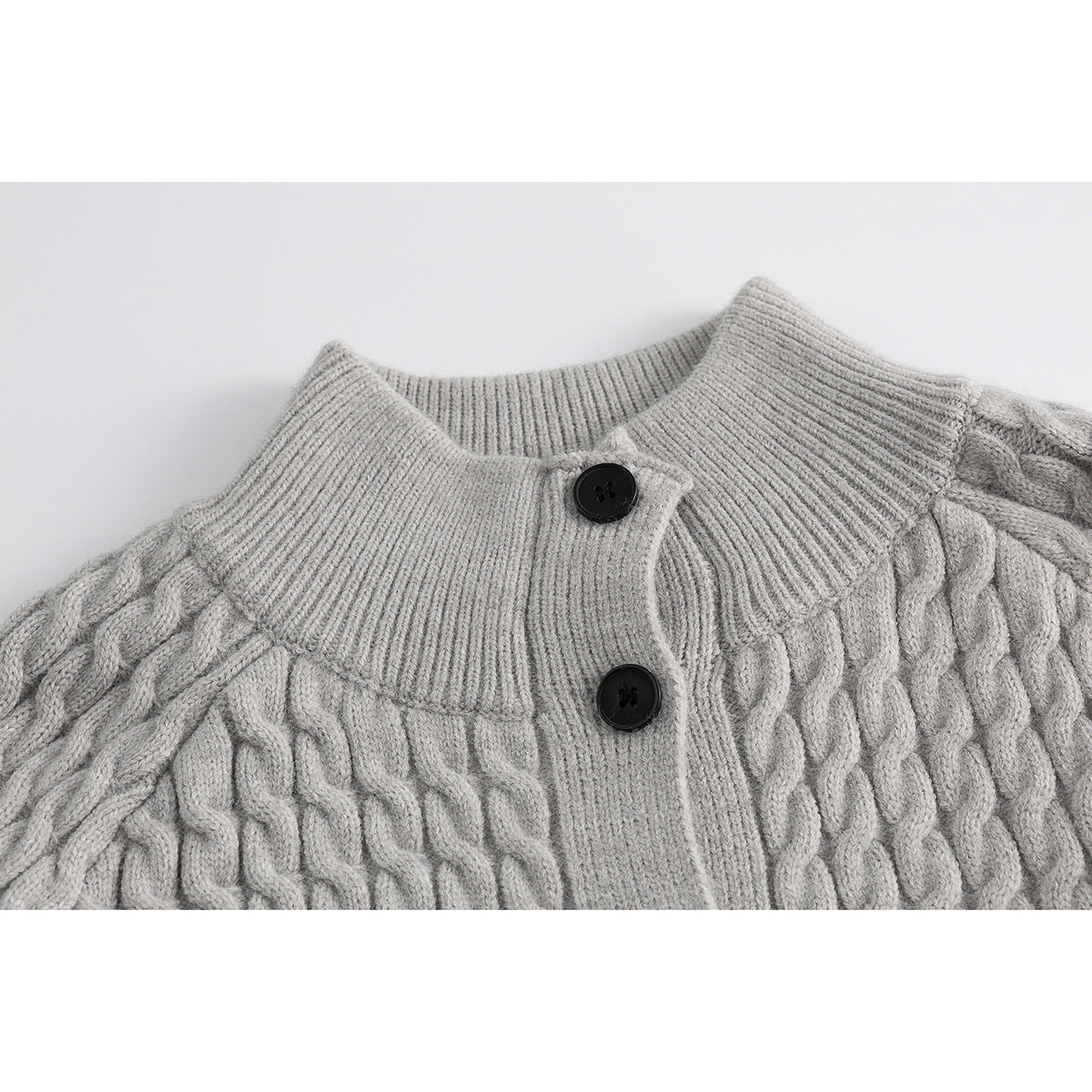 Close-up of a light gray cable-knit cardigan collar and button placket with two black buttons.