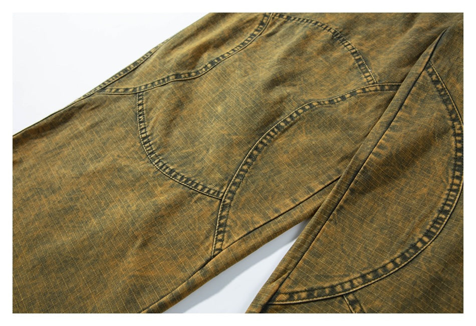 Close-up of ochre-brown mottled pants showing rounded pocket shapes and curved stitched seams.