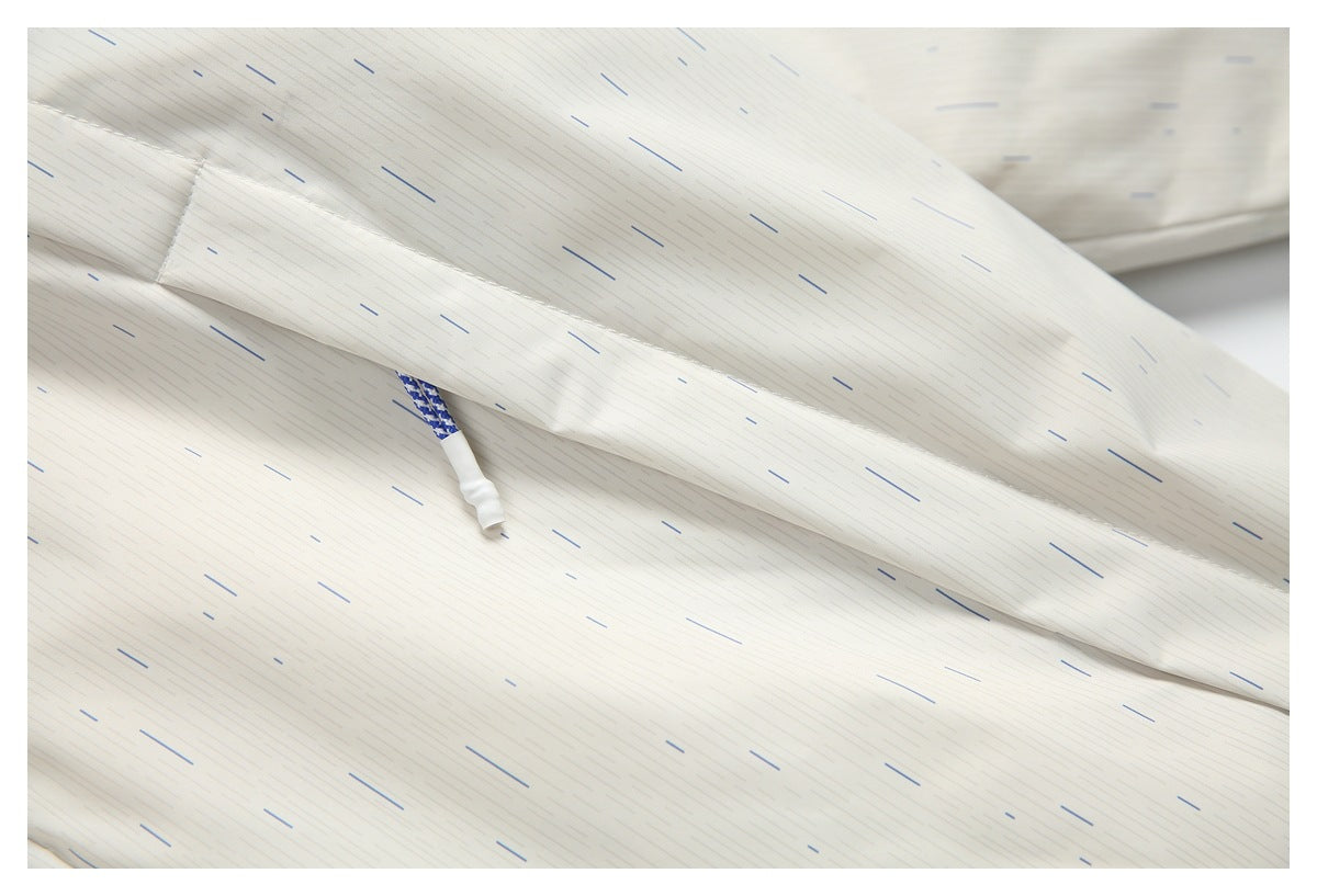 Close-up of a sleeve and cuff on an off-white, finely dashed garment, with a blue-and-white cord end visible beneath.