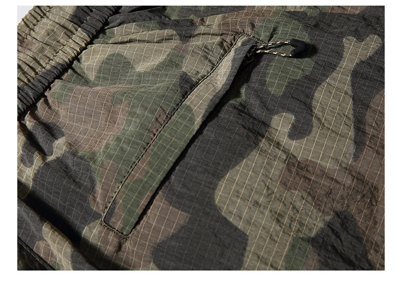 Close-up of a flap pocket and stitching on olive, brown and black camouflage fabric.