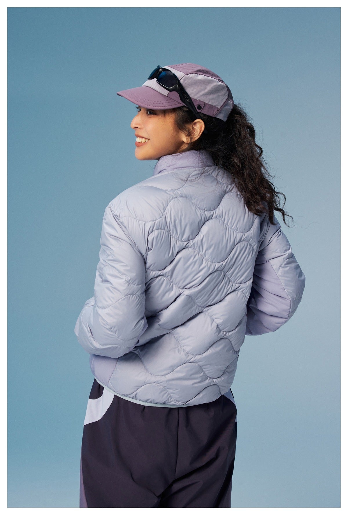 Model shown from behind in a pale lavender wave-quilted jacket with a raised collar.