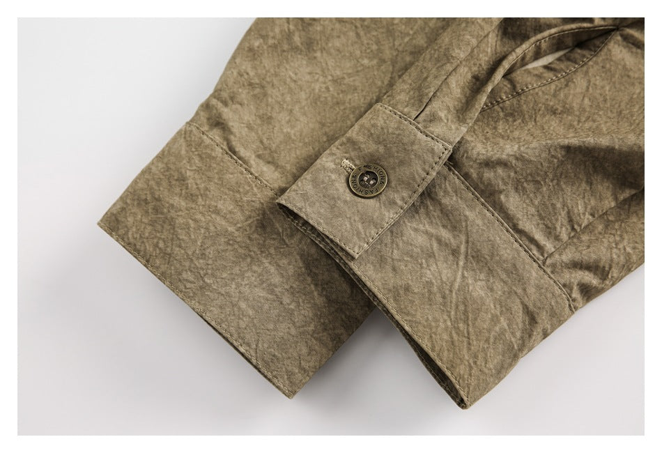 Close-up of a taupe-brown cuff with a button tab, button and visible stitching.