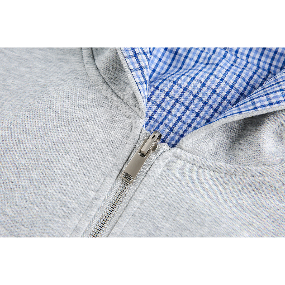 Close-up of a gray hoodie zipper, blue plaid hood lining, and front pocket seam.