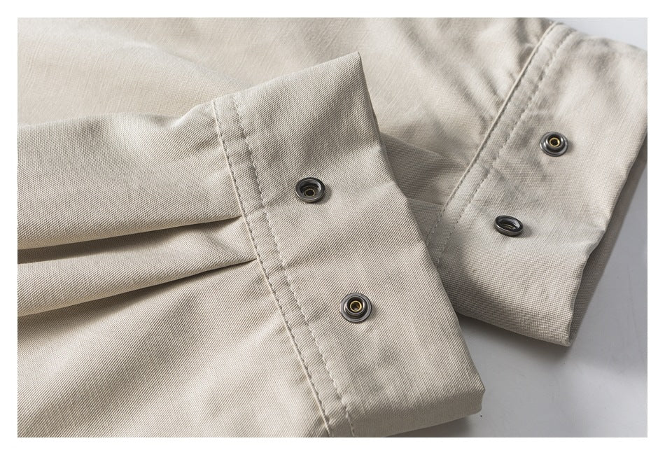 Close-up of a light beige garment cuff with several metal snap fasteners.