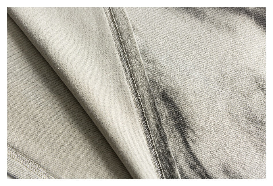 Close-up of light gray-beige garment fabric showing an overlocked seam and folded edge.