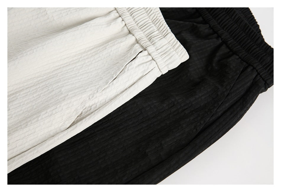 Close-up of white and black textured shorts, showing the gathered waistbands and fabric surface.