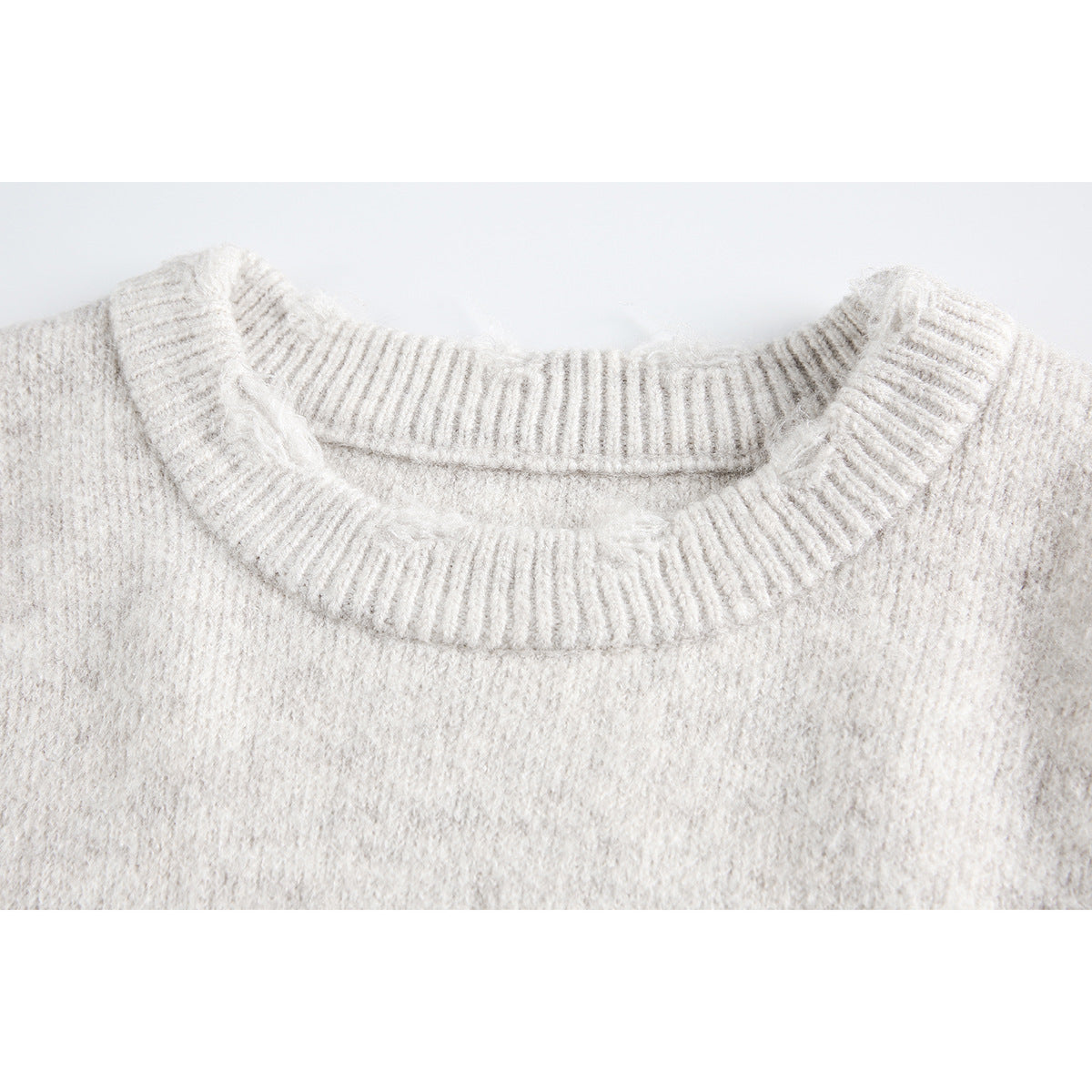 Close-up of an ivory knit sweater's ribbed crew neckline and soft, textured knit.