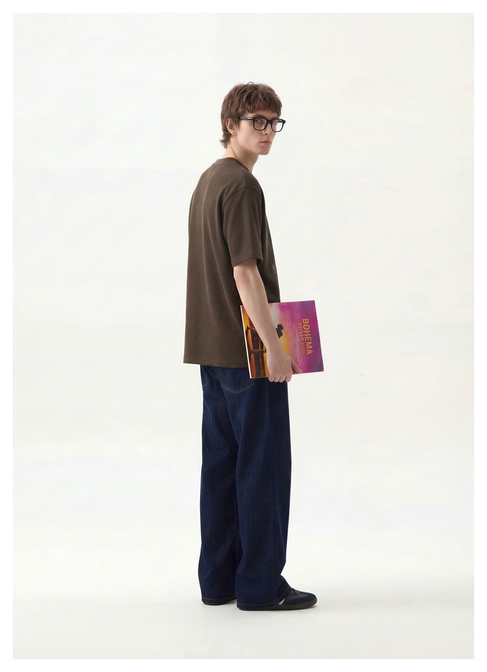 Model wearing the plain back of a dark brown short-sleeve T-shirt with dark wide-leg jeans.