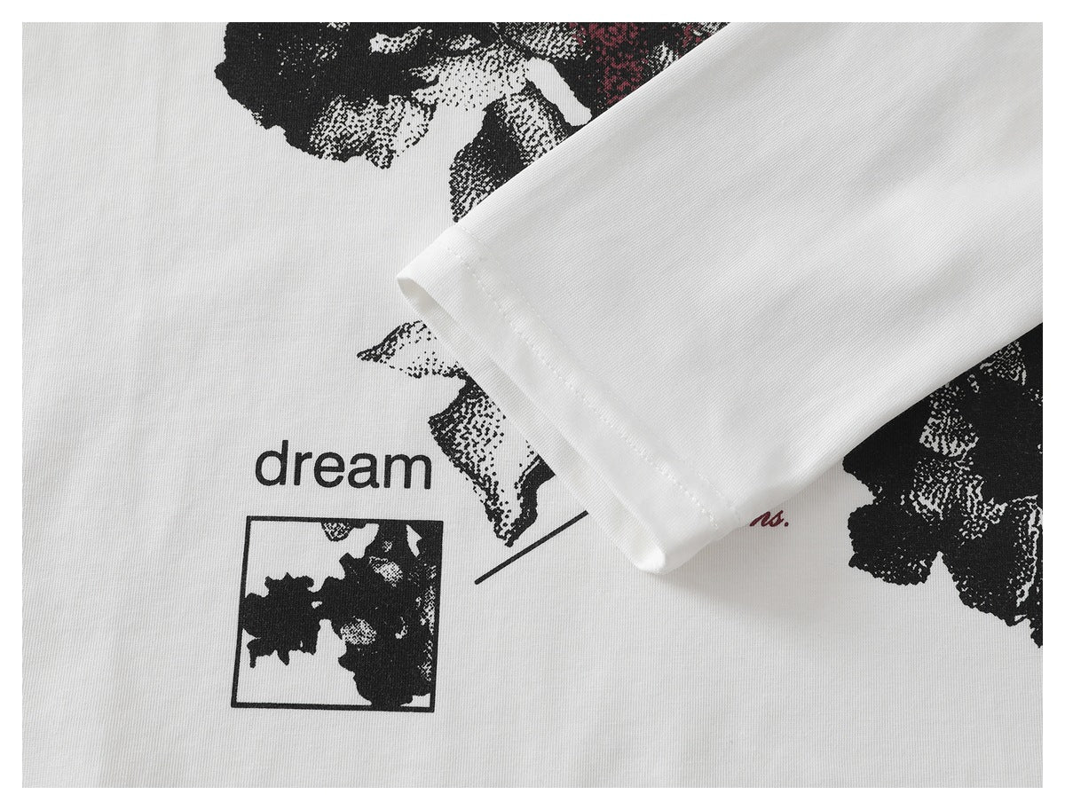 Close-up of a white T-shirt sleeve cuff overlapping part of its black floral print and English lettering.
