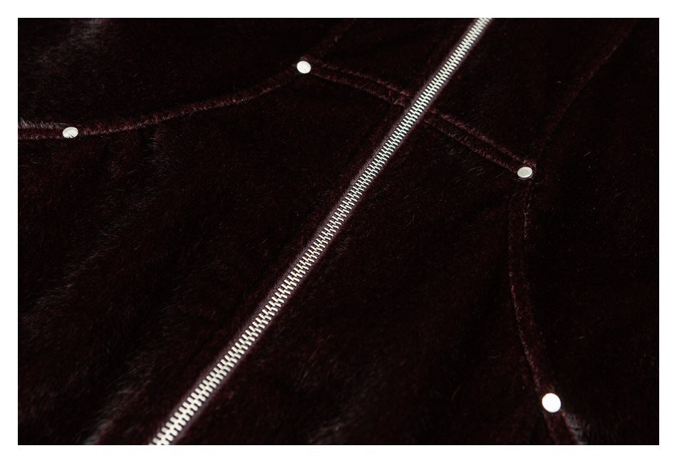 Close-up of a silver zipper and round snaps on dark burgundy plush fabric.